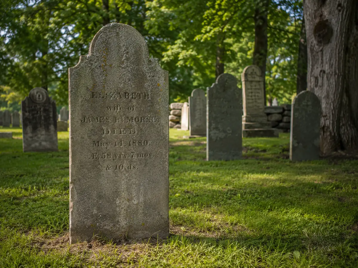 A weathered, historically significant headstone with clear inscription 'Elizabeth, wife of James B. Morse, died May 14, 1880,' surrounded by other old stones in a cemetery—the kind of marker needing specialized restoration care.